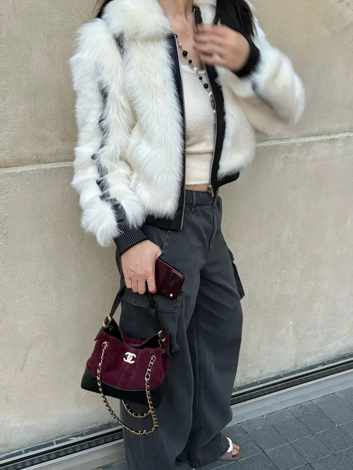Burgundy bag paired with a fluffy off-white jacket, cream top and charcoal cargo trousers